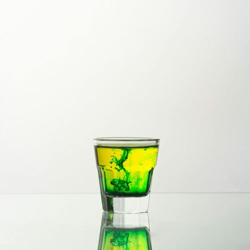 pexels-photo-11434107-11434107 A captivating shot of a vibrant green liquid swirling in a glass, reflecting on a smooth surface.