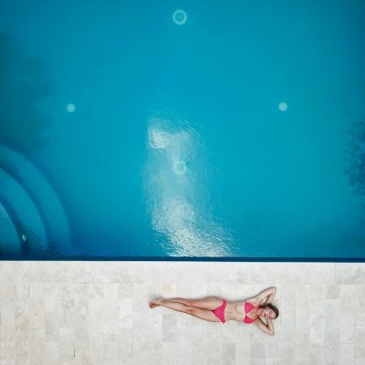 pexels-photo-1460742-1460742 Bird's-eye view of a woman in a pink bikini relaxing by a bright blue swimming pool.