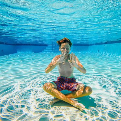 pexels-photo-9044085-9044085 Boy having fun sitting underwater in a sunlit swimming pool.
